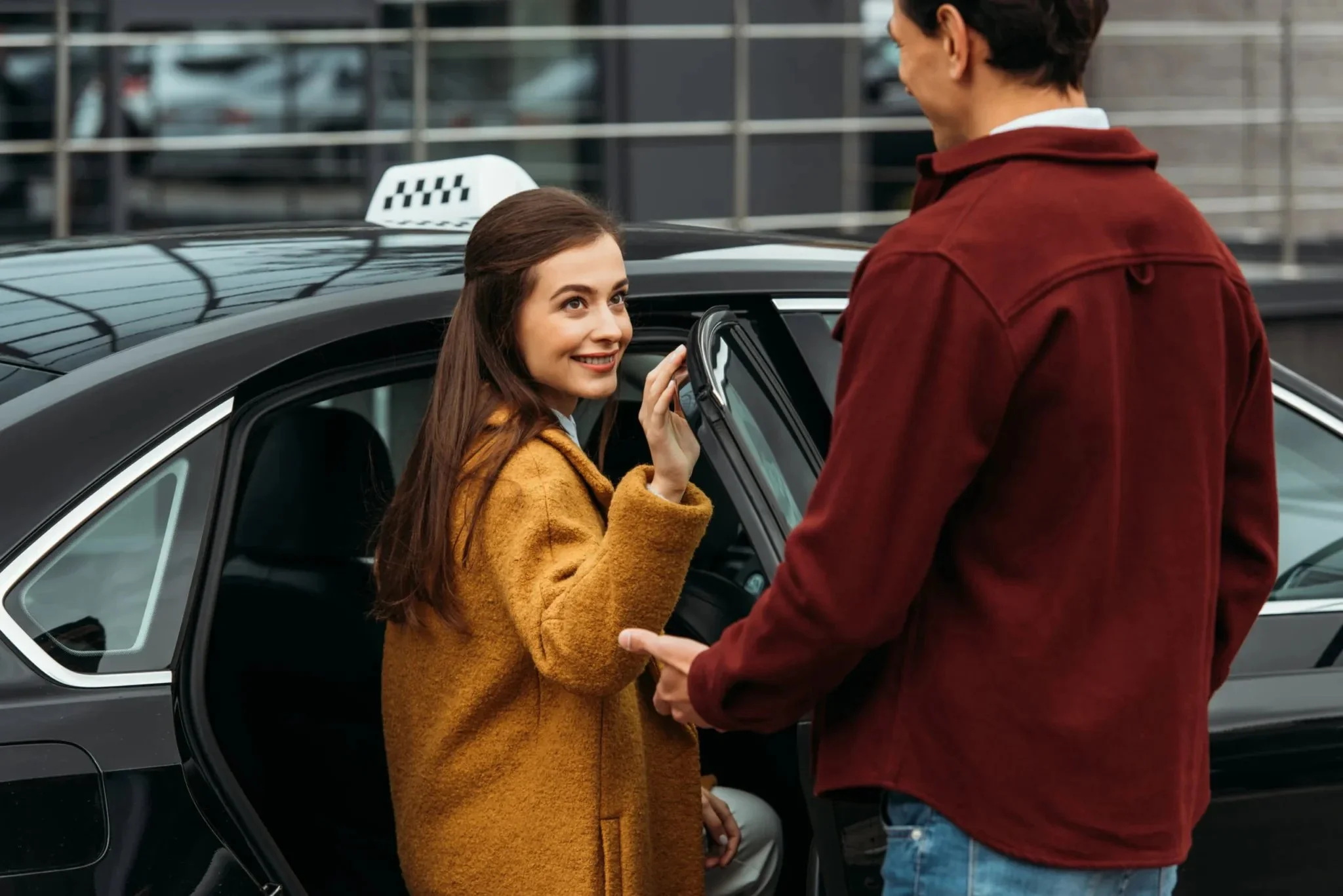 A calm passenger and professional driver standing beside a clean parked car before the ride